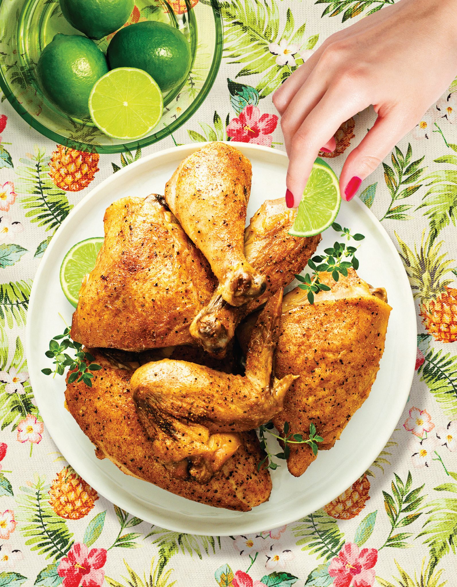 Roasted Cuban mojo chicken with lime wedges, being squeezed over a plated serving.
