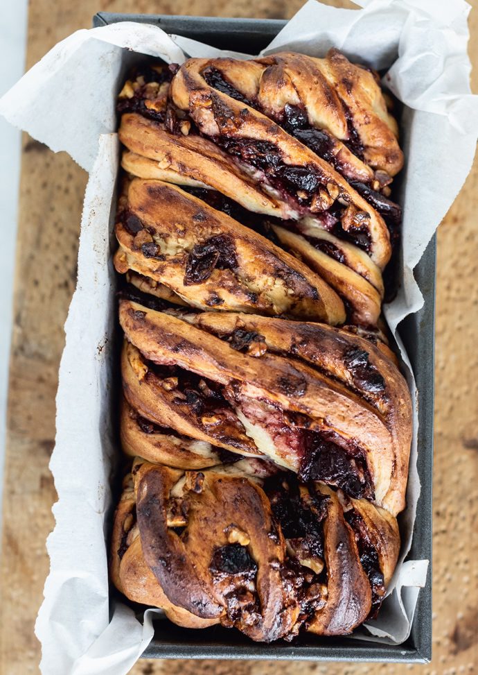 Homemade cherry walnut babka with swirled fruit filling and nuts, baked in a loaf pan and ready to s