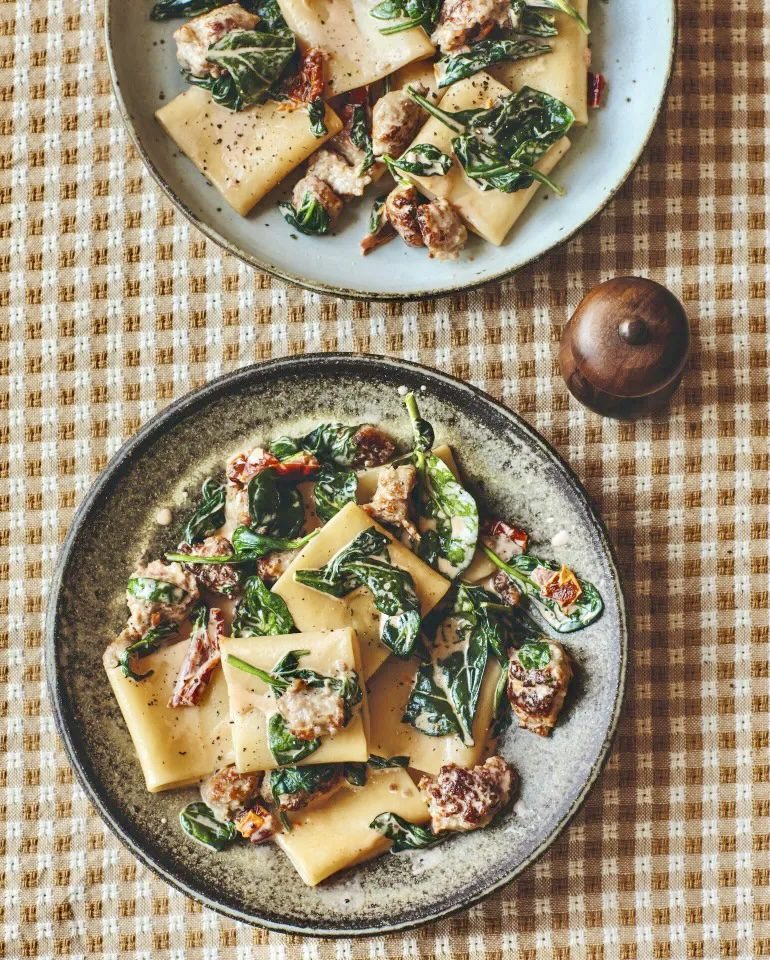Creamy Tuscan Sausage Paccheri with spinach and sun-dried tomatoes, served on rustic ceramic plates 