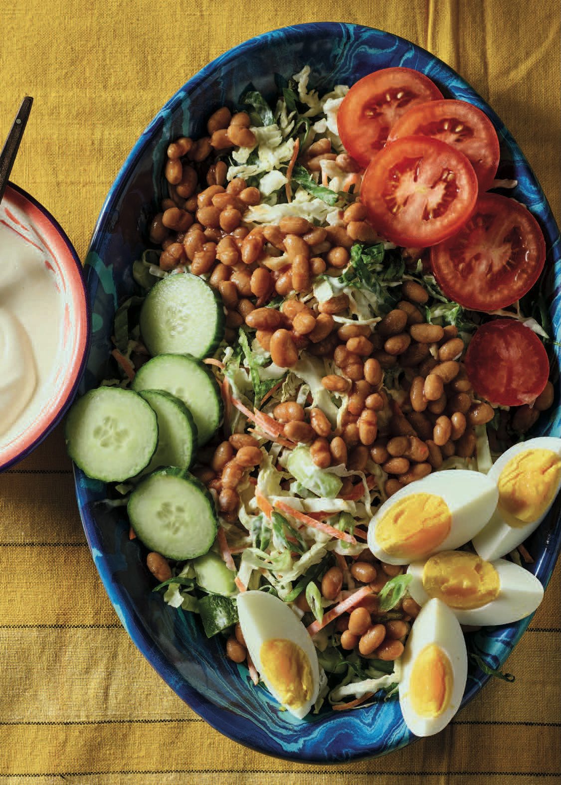 Overhead view of Nigerian Salad in a blue dish. Creamy dressing on the side.