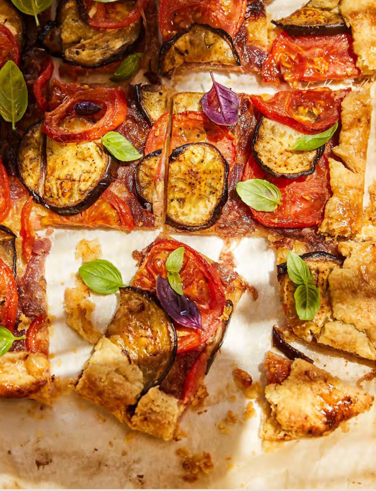Rustic vegetable tart with tomato, aubergine, and fresh basil on a flaky golden crust