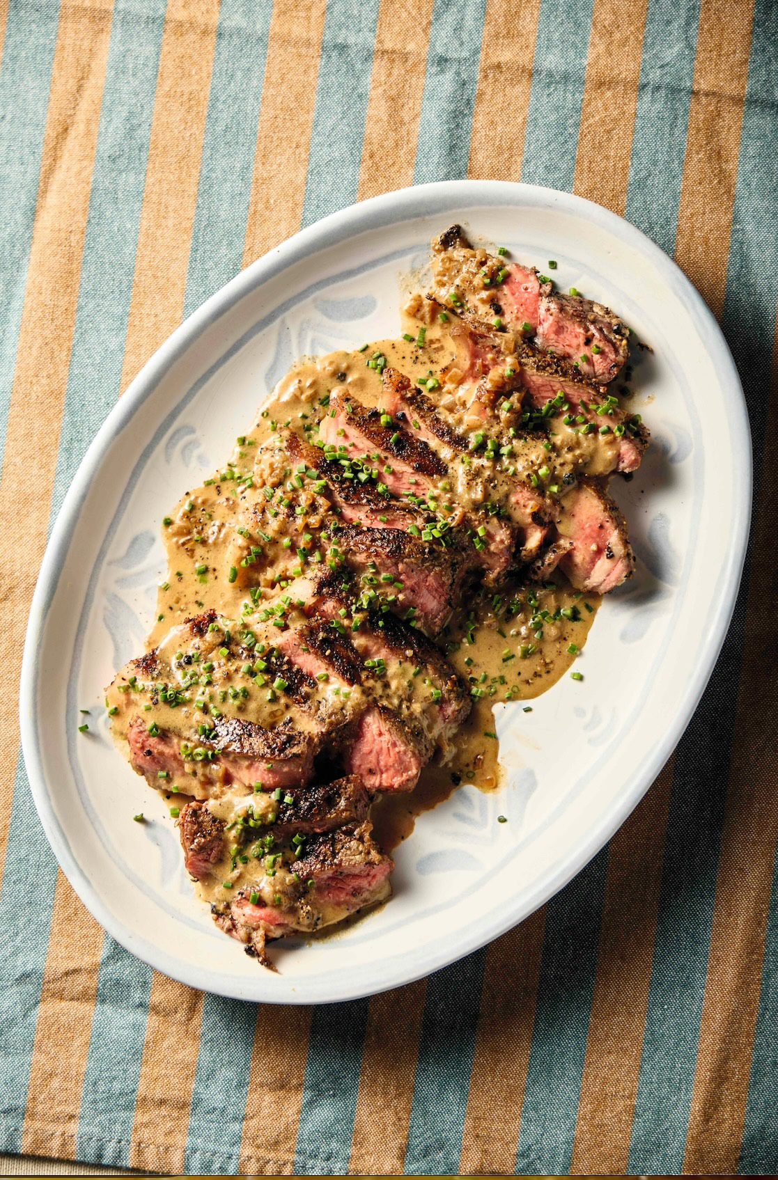 Porcini-crusted steak with creamy mushroom sauce, garnished with chives.
