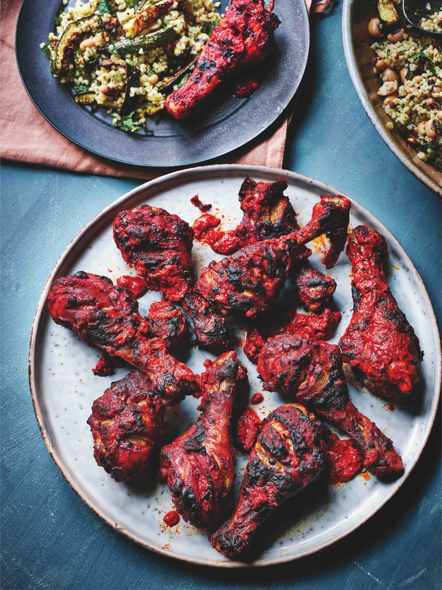 Tandoori-style harissa-marinated chicken drumsticks roasting on baking tray