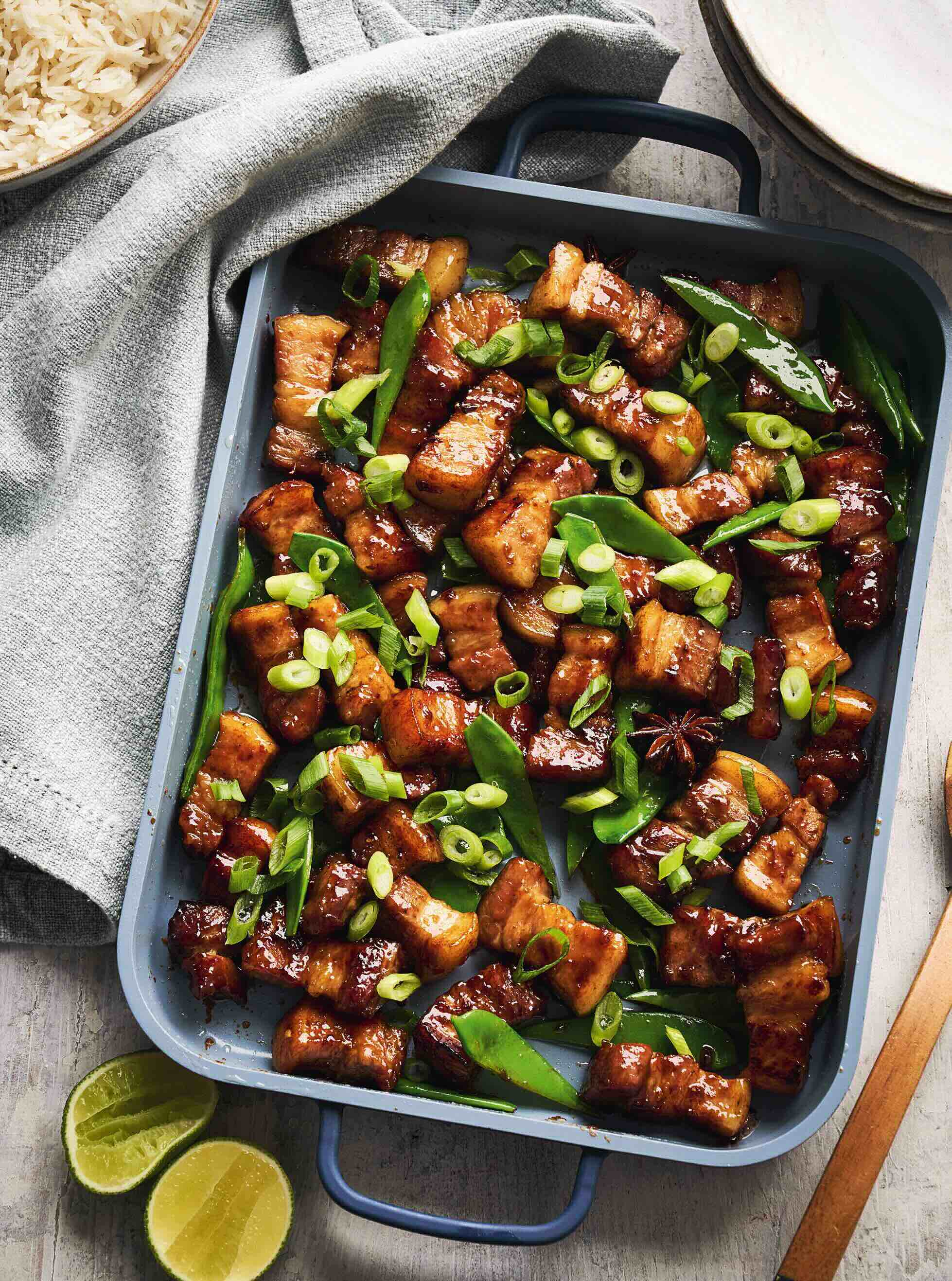 A tray of caramelized Vietnamese style pork pieces mixed with snap peas and sliced green onions.
